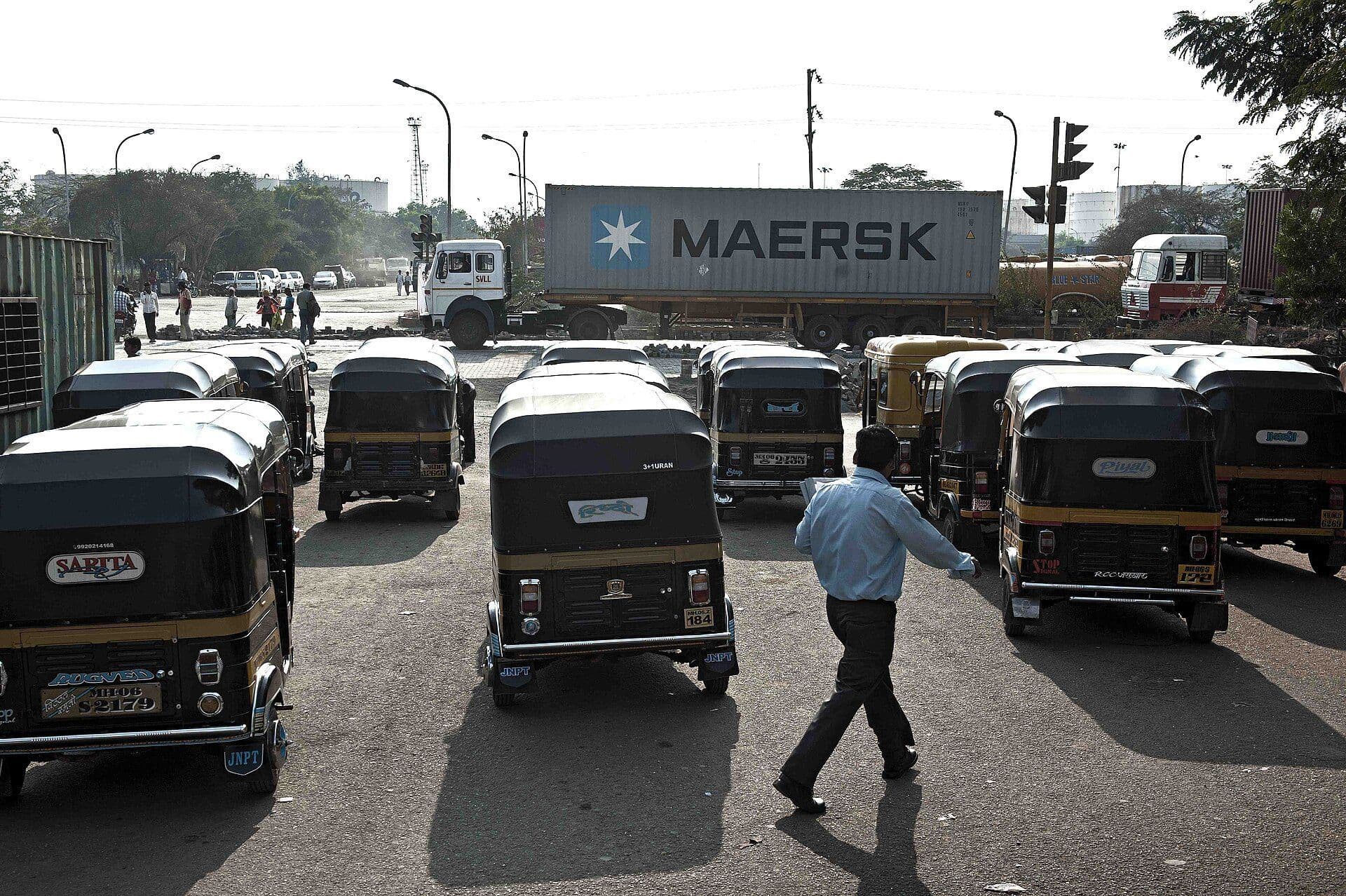 Container truck carrying a shipping container through city traffic in India