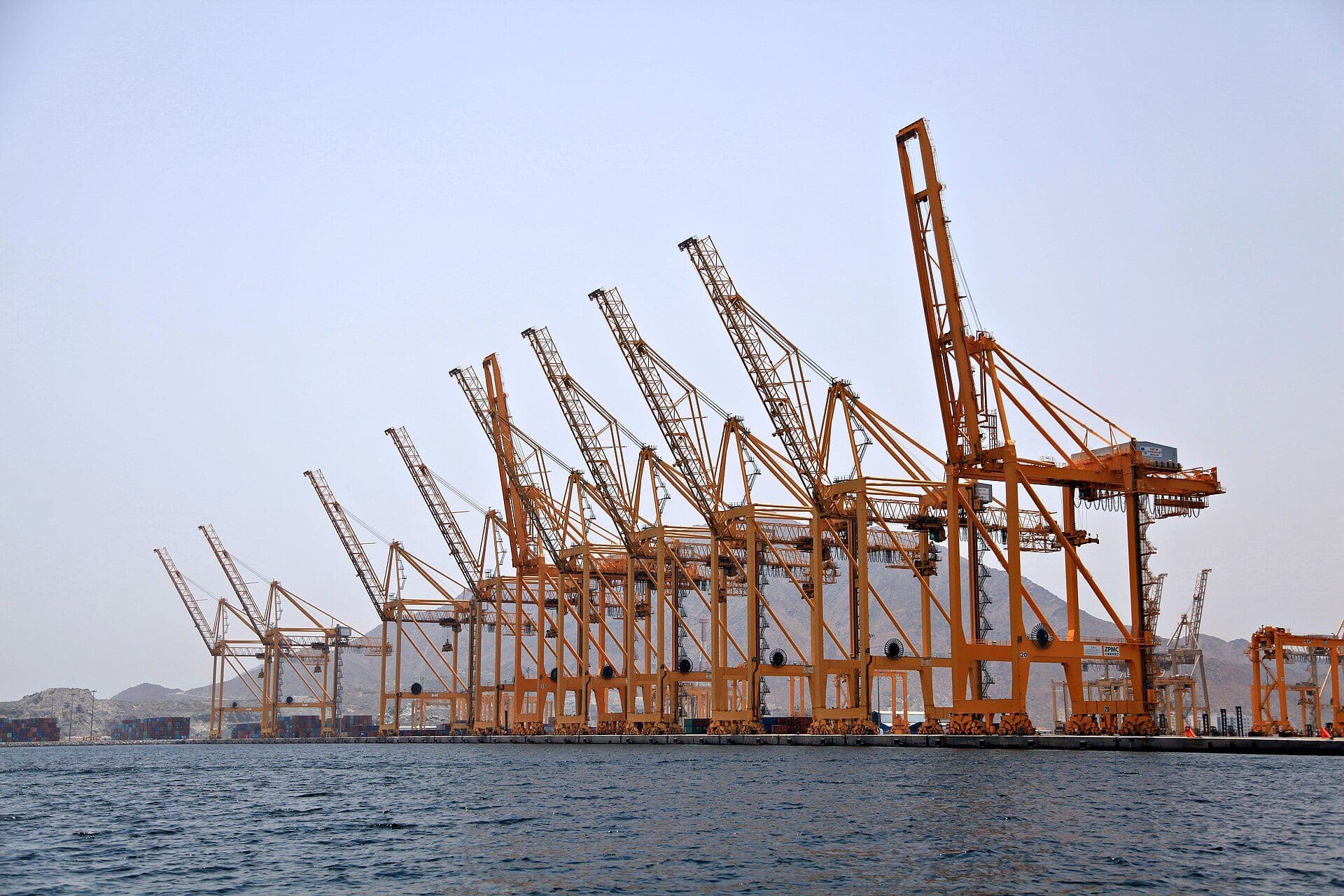 Row of orange ship-to-shore cranes at Khorfakkan container port, Sharjah
