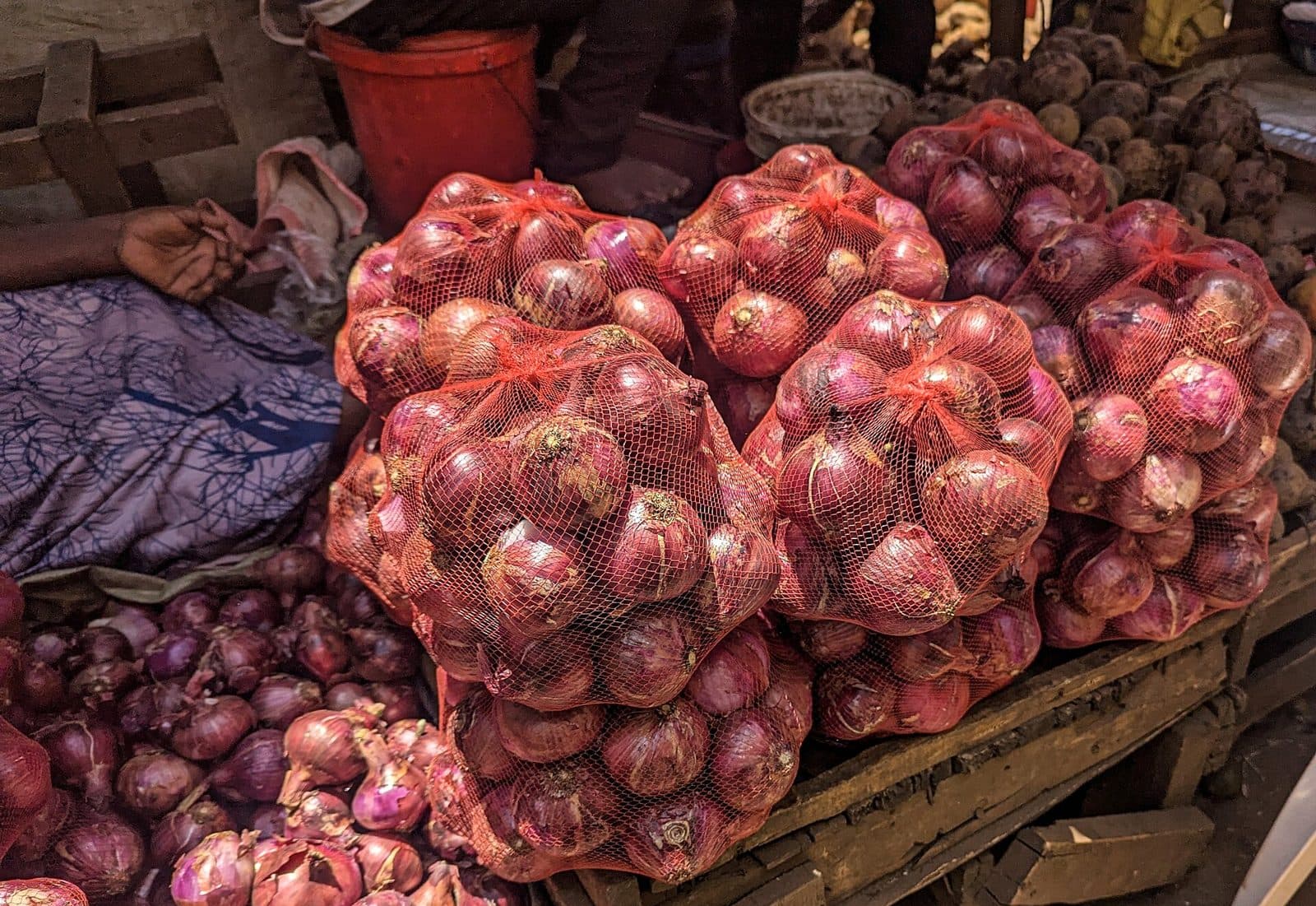 Red onions packed in red mesh bags stacked on a market stall